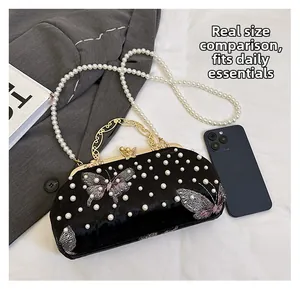 Détail de pochette en velours noir avec broderie papillon violette et chaîne perle