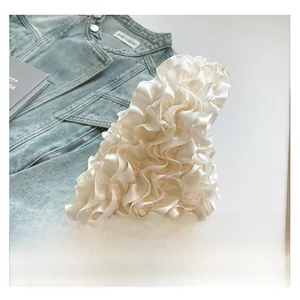 Detailed view of cream ruffled fabric texture with elegant satin finish on mini handbag
