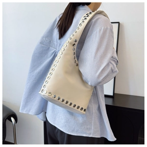 Detail der Hobo-Tasche mit silbernen Nieten auf cremeweißem Leder und Model-Styling