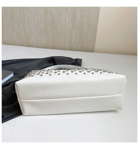 Close-up of white tote bag with silver metal studs against minimalist background