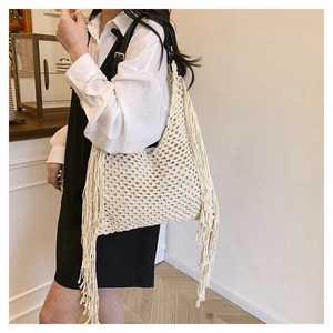 Detail of bohemian cream woven tote bag with fringe tassels and black leather strap