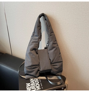 Detail of dark grey quilted puffer tote bag featuring a decorative ribbon bow design