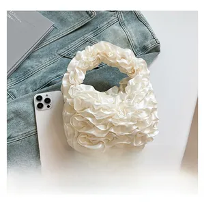 Detail of white pleated handbag with soft ruffled texture on blue denim jacket