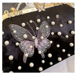 Détail de la pochette en velours avec broderie papillon violette et perles élégantes