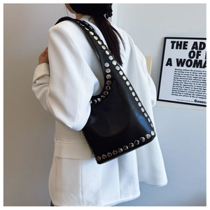 Nahaufnahme der schwarzen Ledertasche mit silbernen Nieten und weißem Blazer