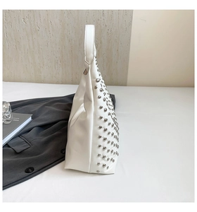 Detail of white leather shoulder bag with dense silver stud accents and sleek finish
