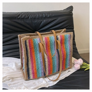 Detail of colorful rainbow woven straw tote bag with brown leather shoulder straps