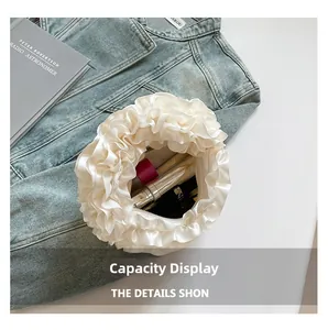 Macro shot of the white satin ruffled bag interior showing cosmetics storage capacity