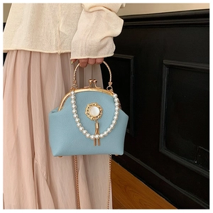 Macro view of light blue beaded shell bag with gold handle and pearl tassel detail
