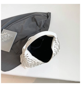 Detailed interior of a white studded crescent bag showing lining and silver rivets