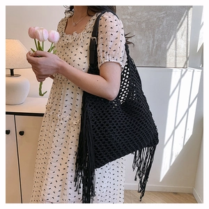 Detail of black handmade crochet tote bag featuring fringe tassels and leather shoulder strap