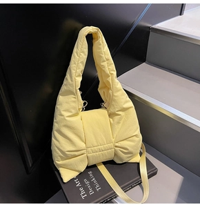 Macro detail of puffy pale yellow nylon shoulder bag with a large decorative bow