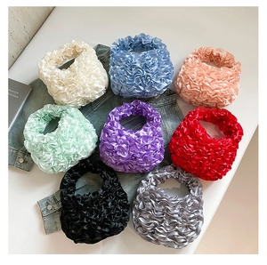 Flat lay of pleated satin bags in eight colors including pastel blue and mint green