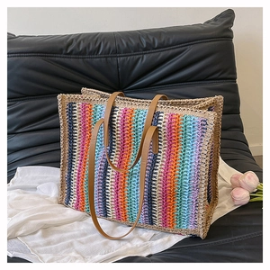 Detail of colorful striped straw tote bag featuring rainbow weaving and brown leather straps