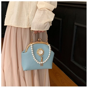 Detailed close-up of light blue leather evening bag with pearls and gold tassels