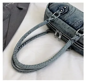 Detailed view of dual zipper closure and rivet decor on vintage denim baguette bag