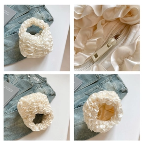 Detail view of white ruffled satin mini bag featuring smooth zipper and soft pleated texture