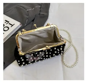Détail de la pochette en velours noir avec perles, broderie papillon et chaîne perle