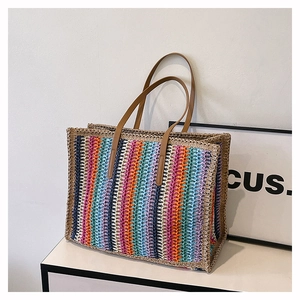 Detail of colorful woven tote bag with rainbow pattern and durable brown leather handles
