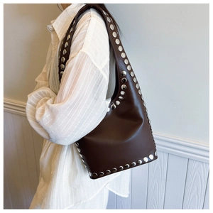 Detail der dunkelbraunen Leder-Achseltasche mit silbernen Metallnieten und Punk-Ästhetik