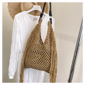 Detail of woven mesh bag featuring long tassels and contrasting black leather strap