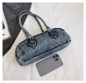 Size comparison of a denim Boston bag with daily essentials on a white fabric background