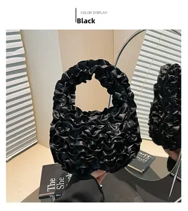 Detailed close-up of a black ruffled handbag with pleated layers and silky texture