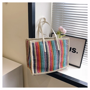 Close-up of rainbow striped straw tote bag with white handles and woven texture