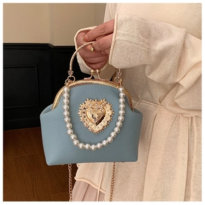Detail of light blue lychee leather bag with golden heart metal relief and pearl chain