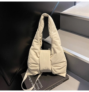 Close-up of cream quilted nylon shoulder bag with a stylish pleated bow design