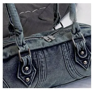 Detail of smooth silver dual metal zippers and stitching on a blue denim Boston bag