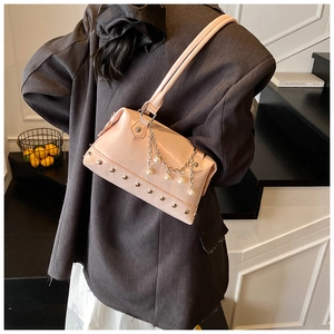 Pink glossy tote bag featuring silver studs and pearl chain detail on a grey suit