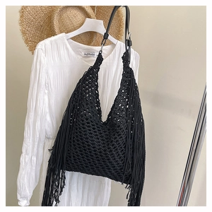 Detail of black bohemian fringe tote with woven mesh texture and long side tassels