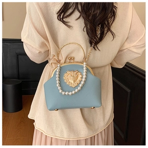 Close-up of light blue pebbled leather bag with golden heart clasp and pearl handle