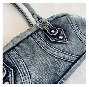 Detailed shot of washed blue denim fabric with silver rivets and white stitching details