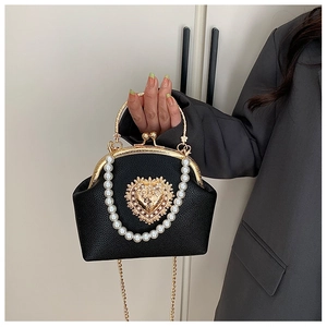 Detail of black lychee leather shell bag with baroque heart ornament and pearl handle