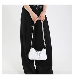 Détail du sac blanc punk avec pointes argentées sur la sangle et boucles métal