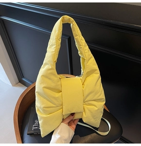 Detail of bright yellow bow-shaped nylon tote bag with puffy padded texture and strap