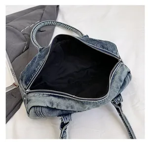 Internal view of blue washed denim shoulder bag with metal zipper and black lining