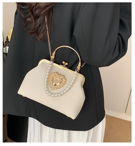 Detail of baroque white handbag with golden hollow heart and elegant pearl handle