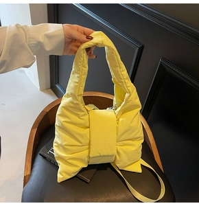 Detail of yellow quilted nylon tote bag featuring a large bow design and detachable strap