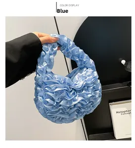 Close-up of light blue pleated satin handbag with ruffles and glossy texture details