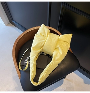 Macro view of pastel yellow bow tote bag with soft padded puffy texture on a chair