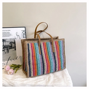 Detailed texture of multi-color striped straw tote bag with brown leather handles