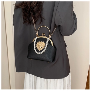 Detail of vintage black shell bag with pearl handle and golden heart ornament