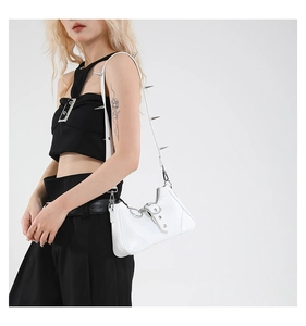 Détail d'un sac à bandoulière en cuir blanc avec des clous argentés sur l'anse
