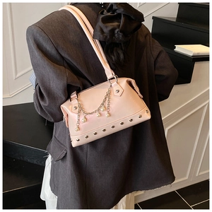 Detail of pink tote bag with pearl pendant chain and silver rivets on leather surface