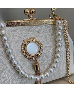 Detail of baroque style bag with engraved gold frame, pearl handle and metal tassel