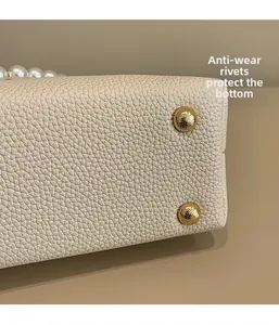 Detail of protective gold studs and litchi texture on white baroque style handbag