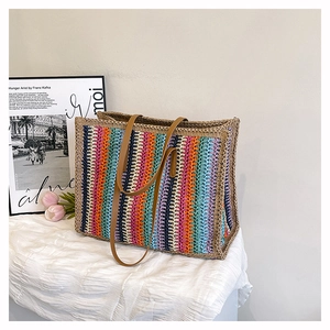 Close-up of rainbow striped straw tote bag with brown leather handles for summer travel